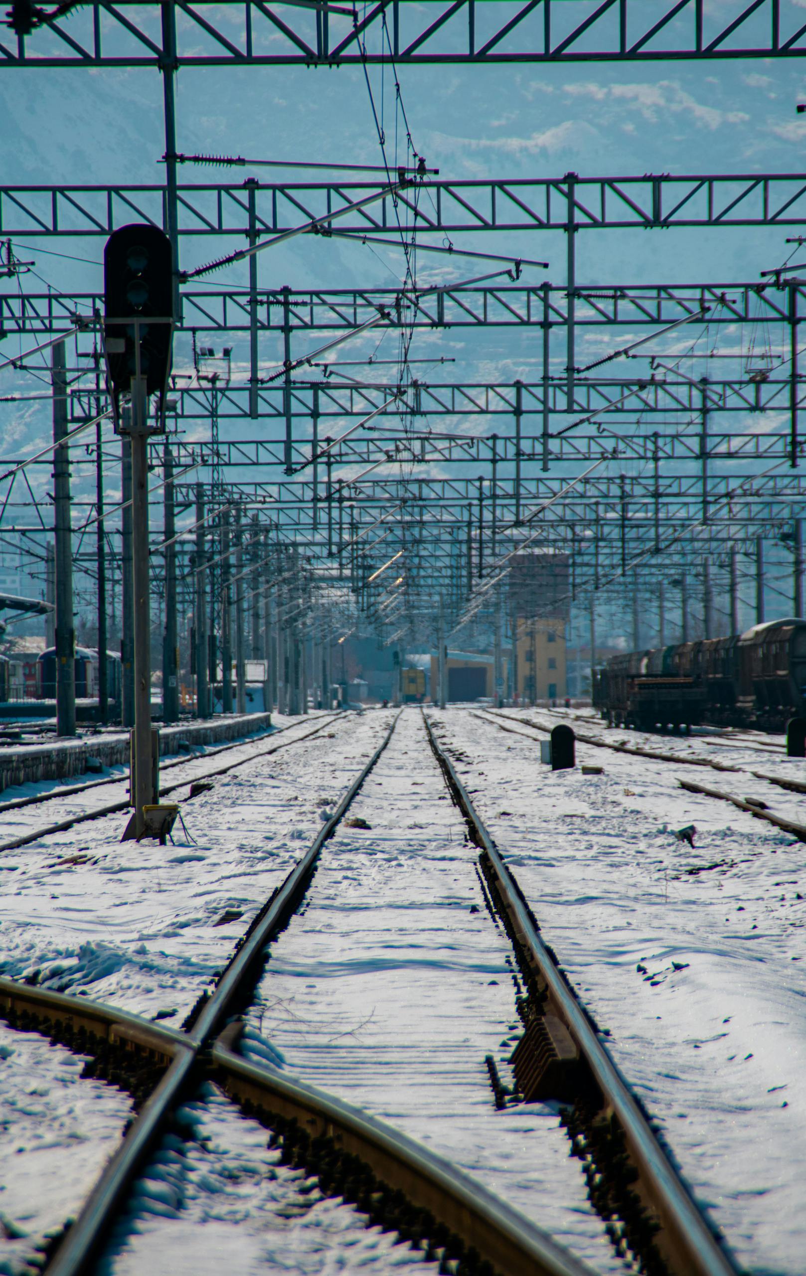 A serene view of snow-covered railway tracks and infrastructure under a blue sky in Kayseri, Türkiye.